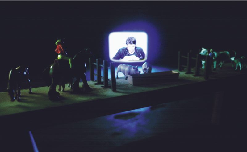 Installation detail: Hintergrund: Guido bei seinem Fernsehauftritt
Vordergrund: Sessel und Spielfiguren