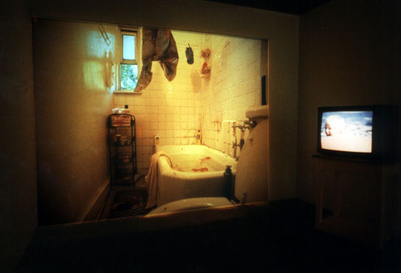 Slide: Present, reality: A bathroom. The water in the bathtub is still let in – plastic fish swim in the tub with their stomach up. The window is open, Anna is no longer there.