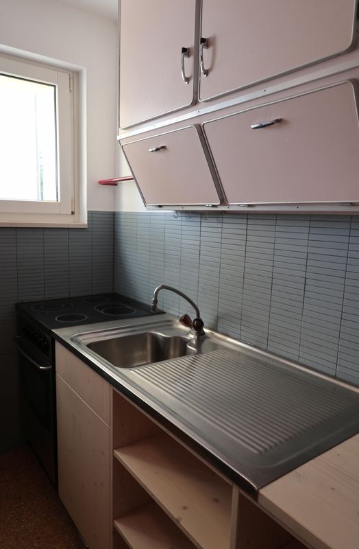 Teilsanierung Küche mit gezielten Eingriffen: Nur dort wo die Fallstränge ersetzt werden mussten, wurde erneuert. Der Wandschrank aus den 1950er Jahren wurde fachgerecht gereinigt und neu gestrichen, die bestehende Arbeitsplatte erhielt einen neuen Unterbau aus geseifter Fichte/Tanne. Das Konzept schafft ein lebendiges Zusammenspiel aus Alt und Neu.
