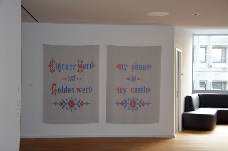 &quot;Eigener Herd ist Goldes wert&quot; und &quot;my phone is my castle&quot;, 2012 Eveline Cantieni kreist mit einer Wandcollage um das paradoxe Verhältnis von trautem Heim und digitalem Nomadismus. Die &quot;Stickarbeit&quot; Cantienis, Kreuzstiche aus Farbe auf Teppichgleitschutzmatte, beschwören häusliche Idylle. Der Spruch &quot;my phone is my castle&quot; auf der einen Matte katapultiert einen aus der trauten Stube in den Orbit der Mobilkommunikation. Christina Peege, Der Landbote, Dezember 2012